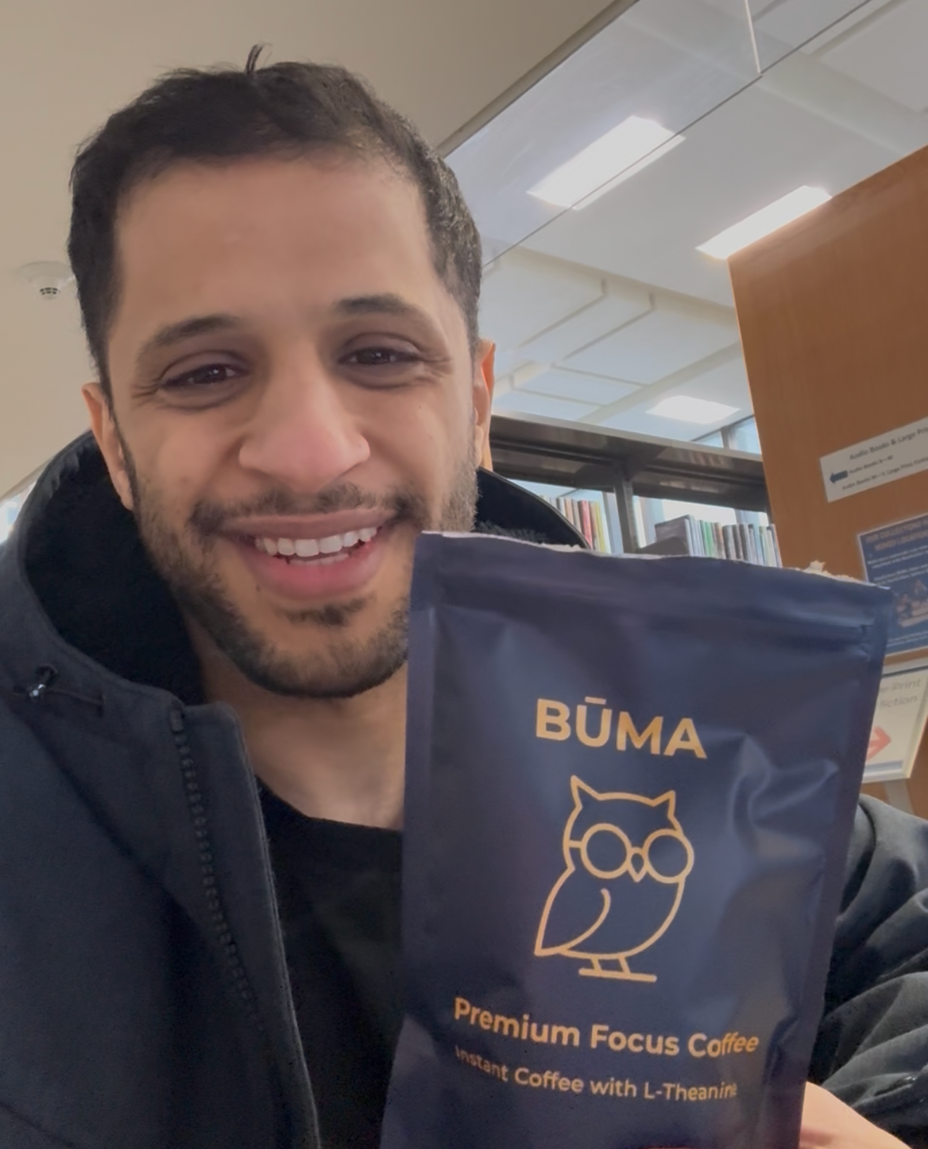 Man holding a BUMA coffee package in an indoor setting